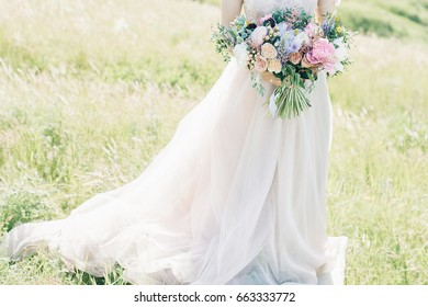 fine art wedding photography. Beautiful bride with bouquet and dress with train in the nature