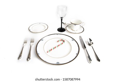 A Fine China Place Setting With A Candy Cane For Christmas Dinner Isolated On White