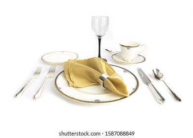 A Fine China Place Setting For Dinner With A Gold Napkin Isolated On White