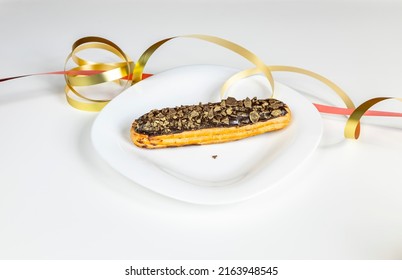 fine delicious eclair served on white plate with golden ribbon and hearts