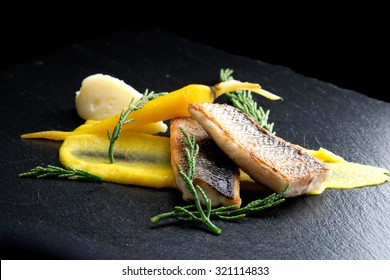 Fine dining Seabass fillets on carrot potato purree and spices