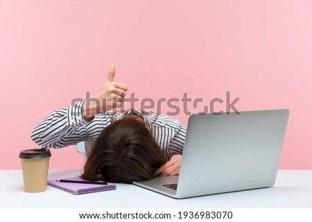 I am fine. Extremely tired sleepy woman lying on table with laptop and cup of coffee showing thumbs up, exhausted with overwork, vitamin deficiency. Indoor studio shot isolated on pink background Сток-фото © 