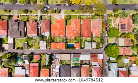 Fine geometry of modern local living suburb of Chatswood in Sydney's North Shore in aerial overhead view over house roofs, back yards, pools and parked cars on the streets.