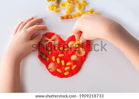 Fine motor skills. Kids creativity. Plasticine modeling for child development at home. Childs hands creating heart from dough for modeling. Anti-stress game with dry pasta Stock photo © 