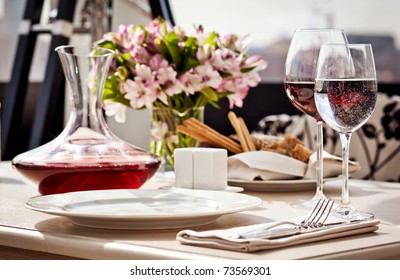 Fine Restaurant Dinner Table Place Setting: Napkin, Wineglass, Plate, Bread And Flowers