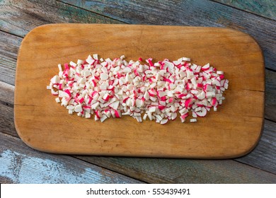 finely chopped crab sticks on cutting board on an old wooden table. close up, top view