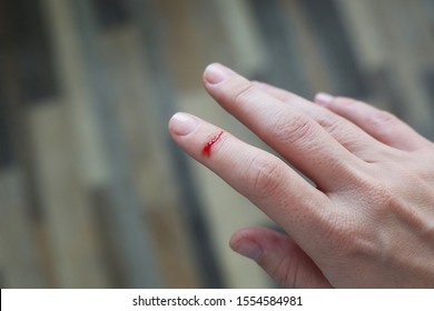 Finger with blood drop. Injured by sharp knife.