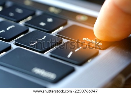 Finger of the computer user, he presses the delete button on the computer keyboard.