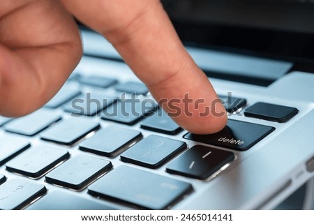 Finger of the computer user, he presses the delete button on the computer keyboard.