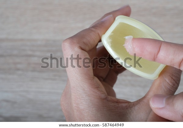 A finger dipped in petroleum jelly jar, skin or\
lip care concept