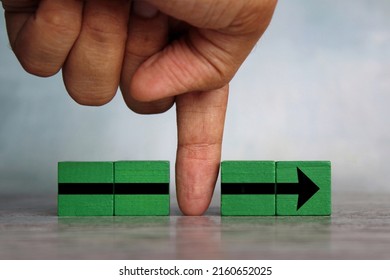 Finger divides the arrow cubes into two parts. Interruption, slowing down process, sabotage concept - Shutterstock ID 2160652025