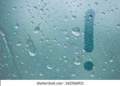 A finger drawing of the shape of an exclamation mark stripe on a semitransparent foggy glass. raindrops of spring rain on the window close-up. blurred background copy space.