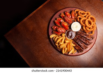 Finger Food Cattail With Chicken Wings In Buffalo Sauce, Onion Rings, Barbecue Pork Ribs And French Fries Top View