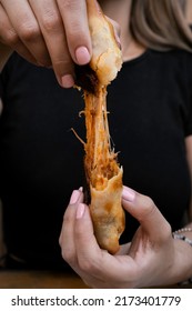 Finger food. Closeup view of a woman cutting a traditional empanada, and stretching the provolone cheese.