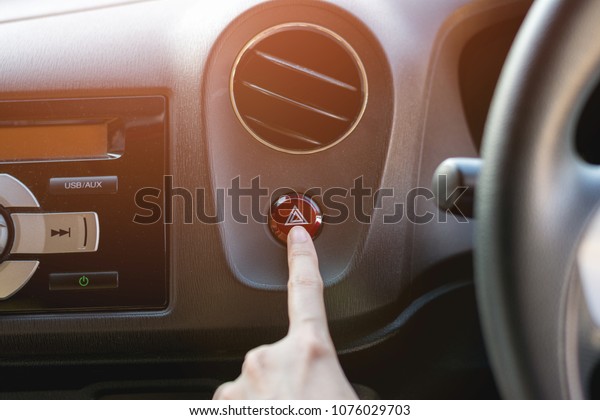 Finger\
hitting car emergency red light button in the\
car.