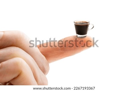 Finger holding small cup of coffee. Concept of small portion 