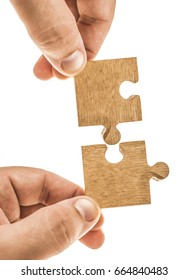 Finger holding two pieces of brown wooden puzzle. Isolated on white background. Slightly de-focused and close-up shot. empty Copy space. hand hold couple of piece on jigsaw