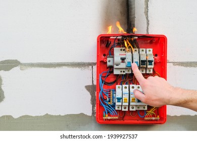 Finger of male hand turns off burning switchboard from overload or short circuit on wall. Circuit breakers on fire from overheating due to poor connection or poor quality wires. Copy space