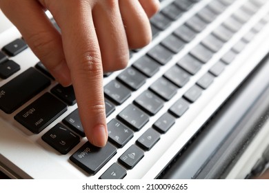 Finger on Delete button. Woman working at home, with hand on Thai keyboard. Young woman working on computer at table in hotelroom. Hands of an office woman typing.