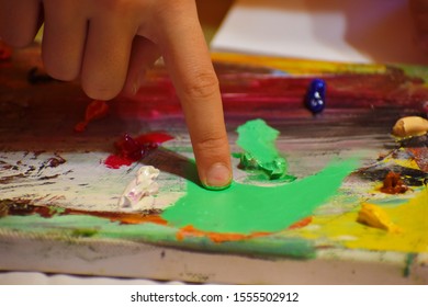 Finger Painting With Oil Paints. A Child Poked Into The Artist's Palette. Art Studio. Child Learn To Draw. Children's Art Therapy.