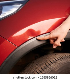 Finger point at car scratch near wheel area