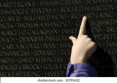 a finger points out a name inscribed at the Vietnam Veterans Memorial in Washington, DC