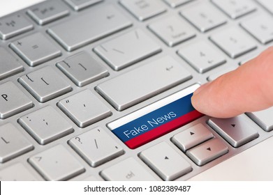 A finger press button with Russian flag on laptop keyboard and inscription fake news.