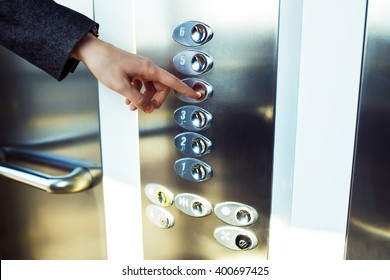 finger presses the elevator button. Red button. sunset light. businessman is a lift. high floor. hand reaches for the button of the elevator call.
