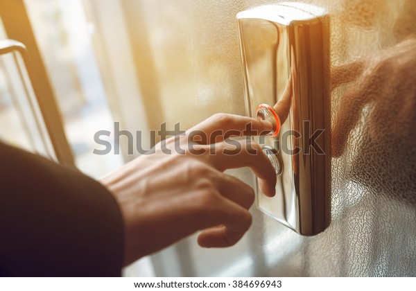 finger presses the elevator button. Red button.\
sunset light. businessman is a lift. high floor. hand reaches for\
the button of the elevator\
call.