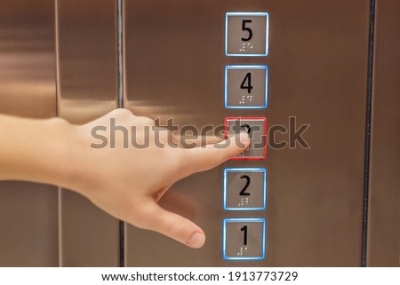 finger presses the number on the elevator button