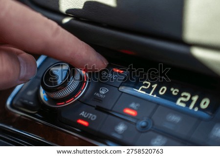 Finger presses SYNC button on car climate control panel, synchronizing dual zone temperature settings in vehicle interior.