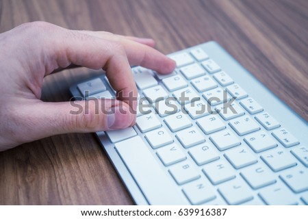 Finger pressing alt-tab command on the white wireless keyboard.