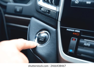 Finger pressing button the start button, stop the engine in the luxury car. The man's finger is pressing down. Owner and dealership concept, auto dashboard, the man behind the wheel