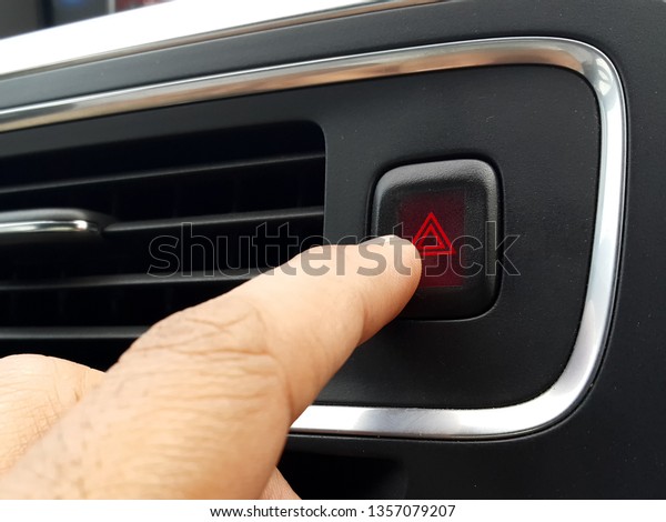 Finger pressing car\
emergency red light button or the hazard warning light triangle\
logo button in the car