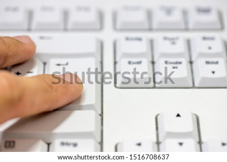 Finger pressing the enter button on a PC keyboard