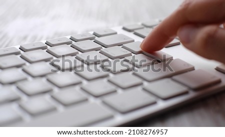 Finger pressing an enter key. Computer user hitting the enter key, up close. Confirmation, sending a message