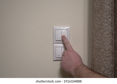 Finger Pressing Light Switch To Turn Off The Light. Modern White Light Switch On White Wall