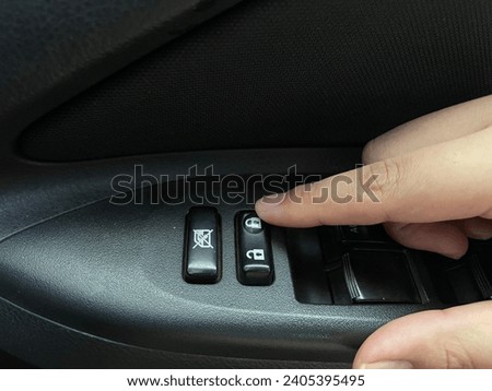 Finger pressing the lock button inside the car