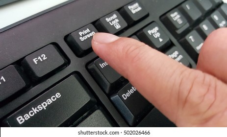 Finger Pressing Print Screen Command On The Keyboard.