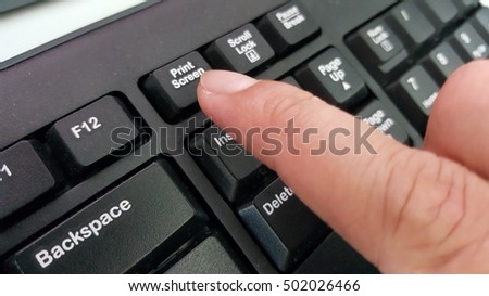 Finger pressing print screen command on the keyboard.