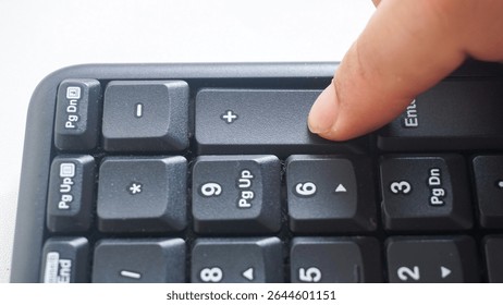 Finger pressing punctuation key button on a black modern wireless computer keyboard isolated on white background
