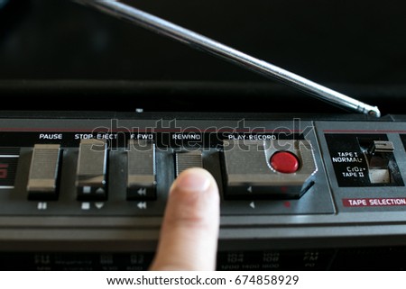 Finger pressing the Rewind button on an old stereo 80's