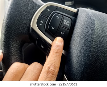 finger pressing the voice command button on the steering wheel of a modern car.  voice command technology makes it easy for car drivers to communicate while driving a car on the go