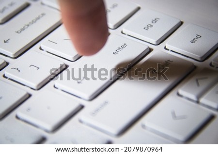 Finger pressing the white keyboard. Index finger. Man pressing the enter button of the computer. White keyboard of a laptop.