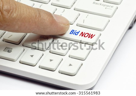 Finger push Bid Now button on white keyboard - Business Concept