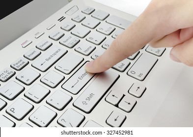 Finger pushing enter button on laptop keyboard