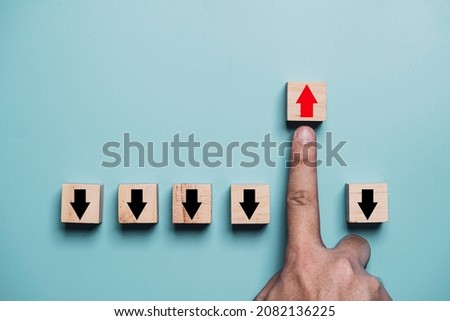 Finger pushing red up arrow which it opposite direction from black down arrow for business disruption and leadership concept.