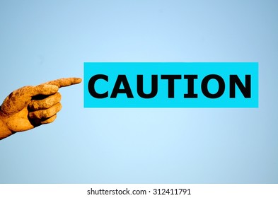 finger with rectangular light blue label CAUTION