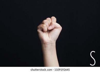 Finger spelling alphabet. Female hands isolated on blue background showing deaf mute BSL alphabet letter S                               