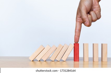 Finger stopping the domino effect on wooden table. Business Risk management concept. Business strategy